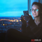 videoblocks-hipster-girl-looking-at-smartphone-on-night-city-lights-background-young-woman-in-glasses-using-mobile-phone-and-liking-photos-beautiful-casual-female-chatting-and-using